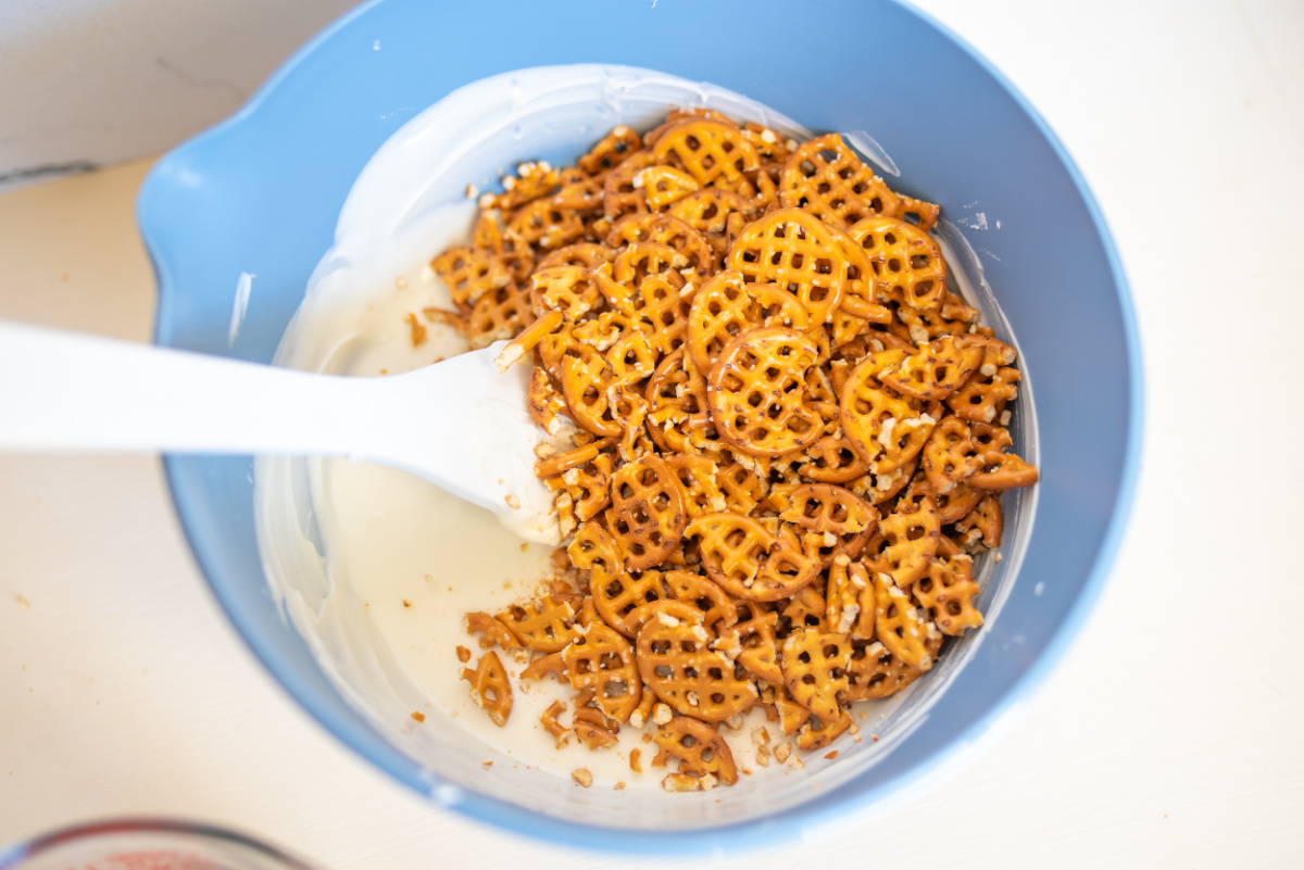 adding crushed pretzels to melted chocolate