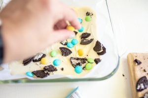 adding candy and cookie pieces to white chocolate