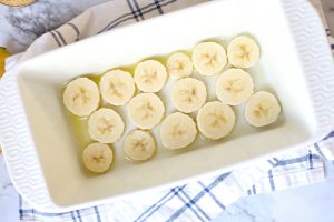 banana slices placed in bottom. of bread pan