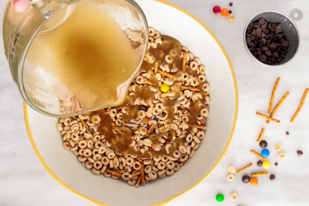 pouring melted butter mixture over cereal mix