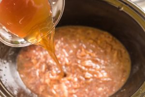 broth being poured into slow cooker