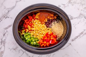 black beans, red enchilada sauce, diced tomatoes and green chiles, frozen corn, beef broth, uncooked rice, and bell peppers added to slow cooker