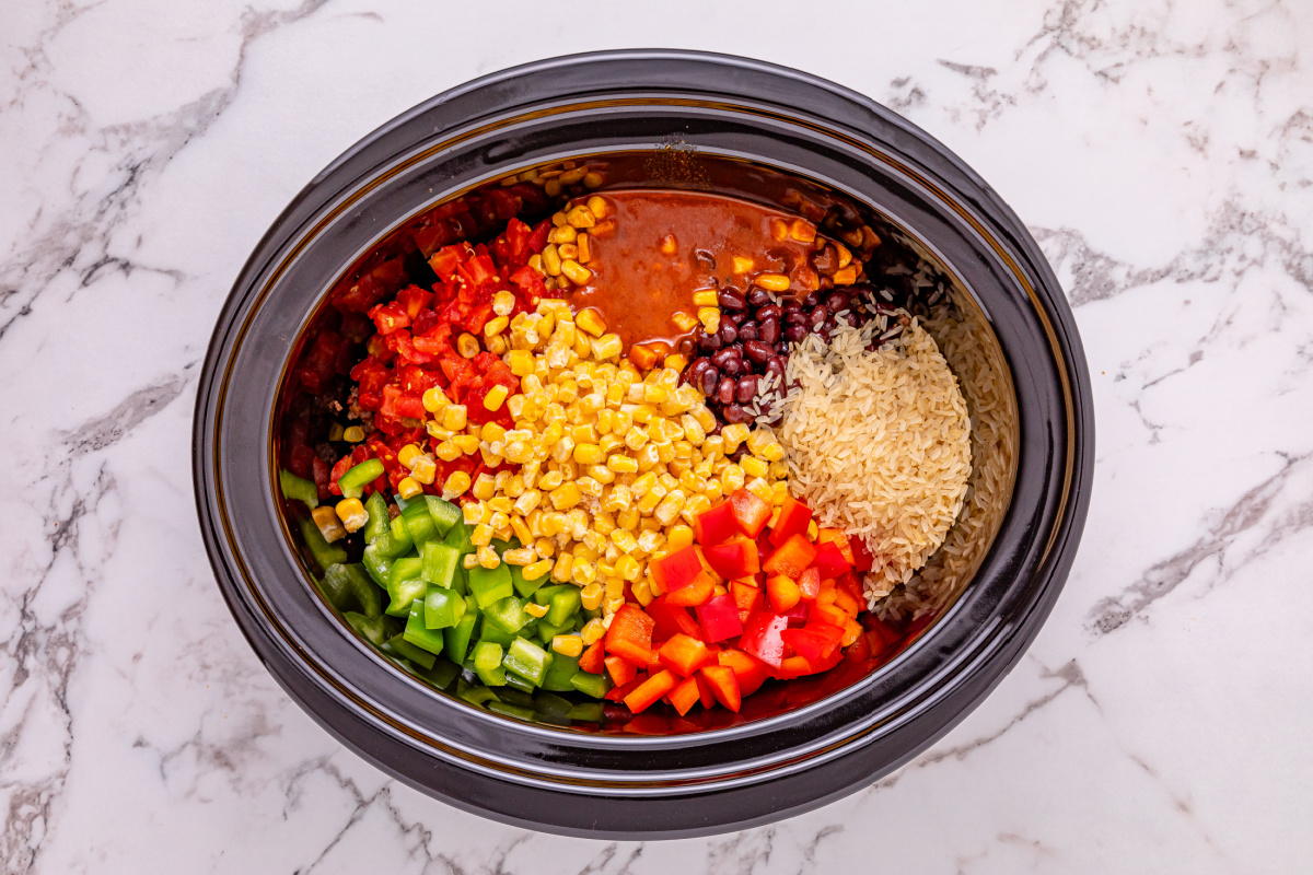 black beans, red enchilada sauce, diced tomatoes and green chiles, frozen corn, beef broth, uncooked rice, and bell peppers added to slow cooker