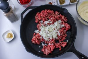 beef cooking in pan with diced onions