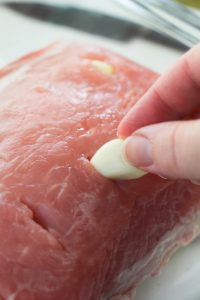 placing garlic cloves into pork