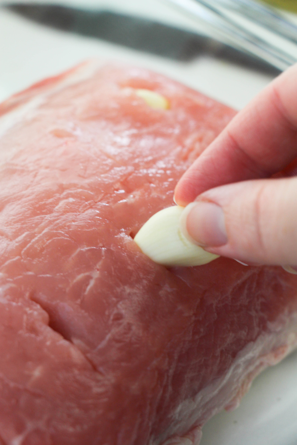 placing garlic cloves into pork