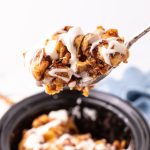 Slow Cooker Cinnamon Roll Casserole in a slow cooker with a serving spoon