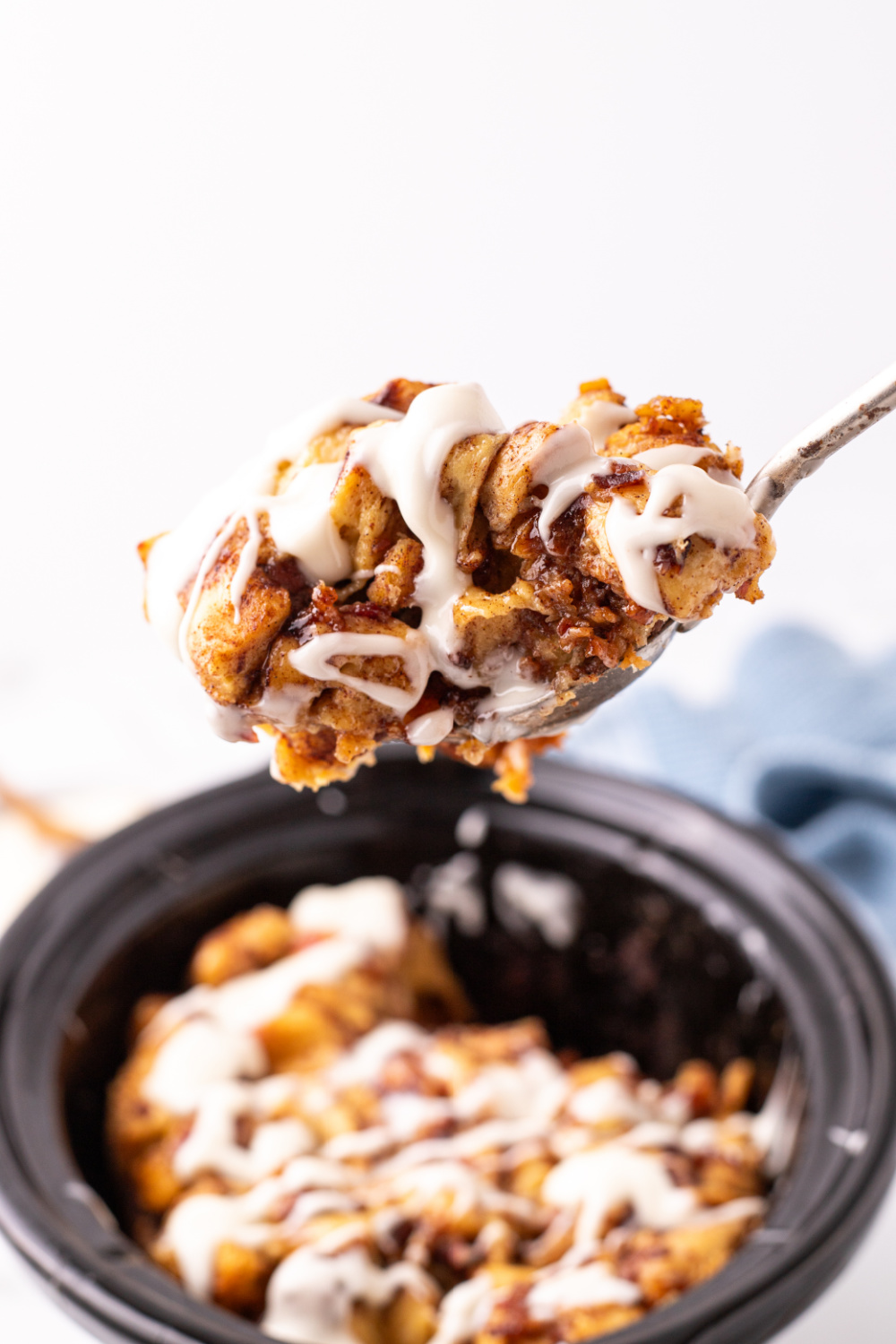 Slow Cooker Cinnamon Roll Casserole in a slow cooker with a serving spoon