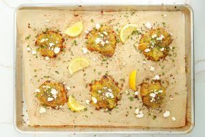 Crispy Greek Smashed Potatoes on a baking sheet with feta cheese and lemons