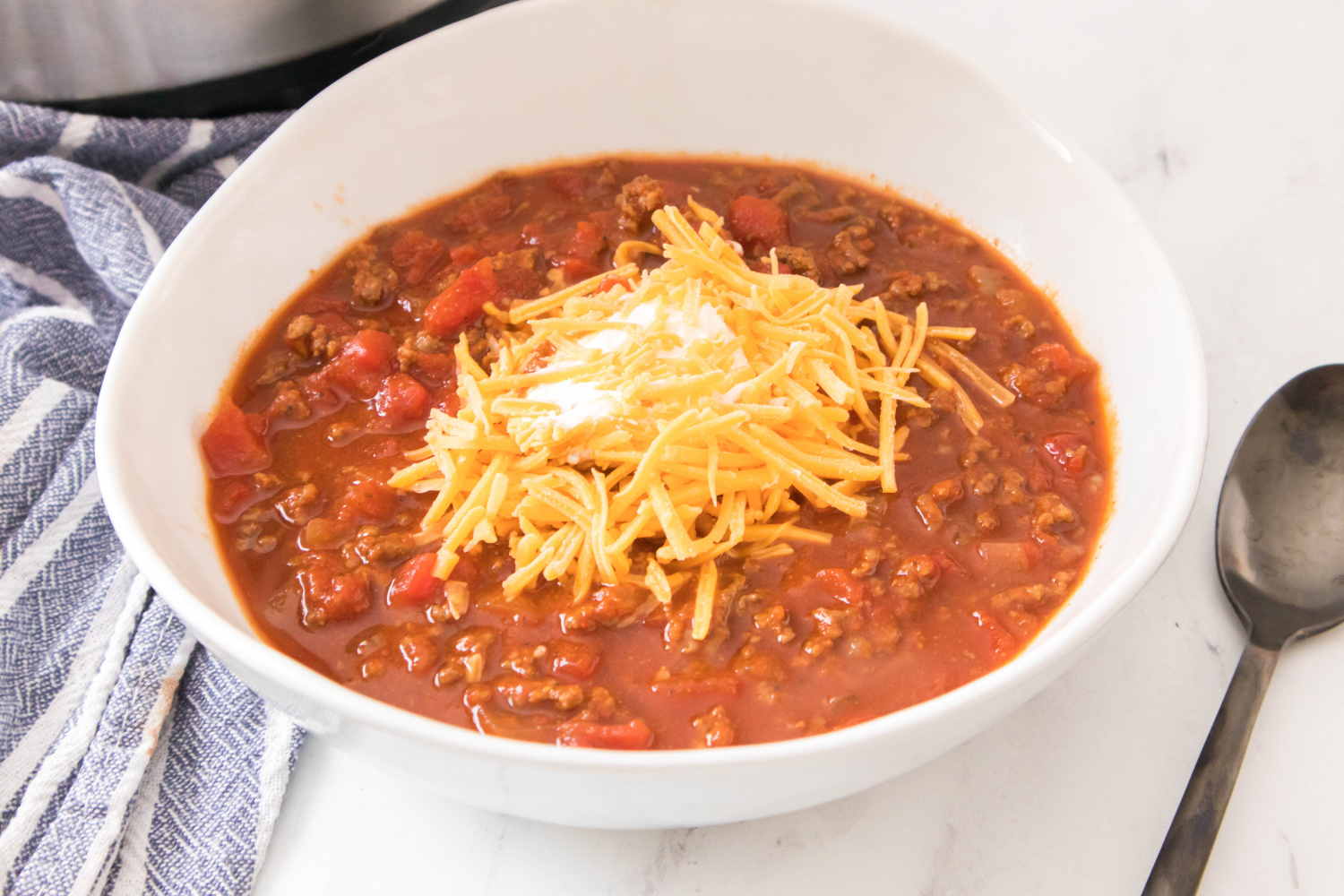Easy Instant Pot Chili in a bowl topped with sour cream and shredded cheese