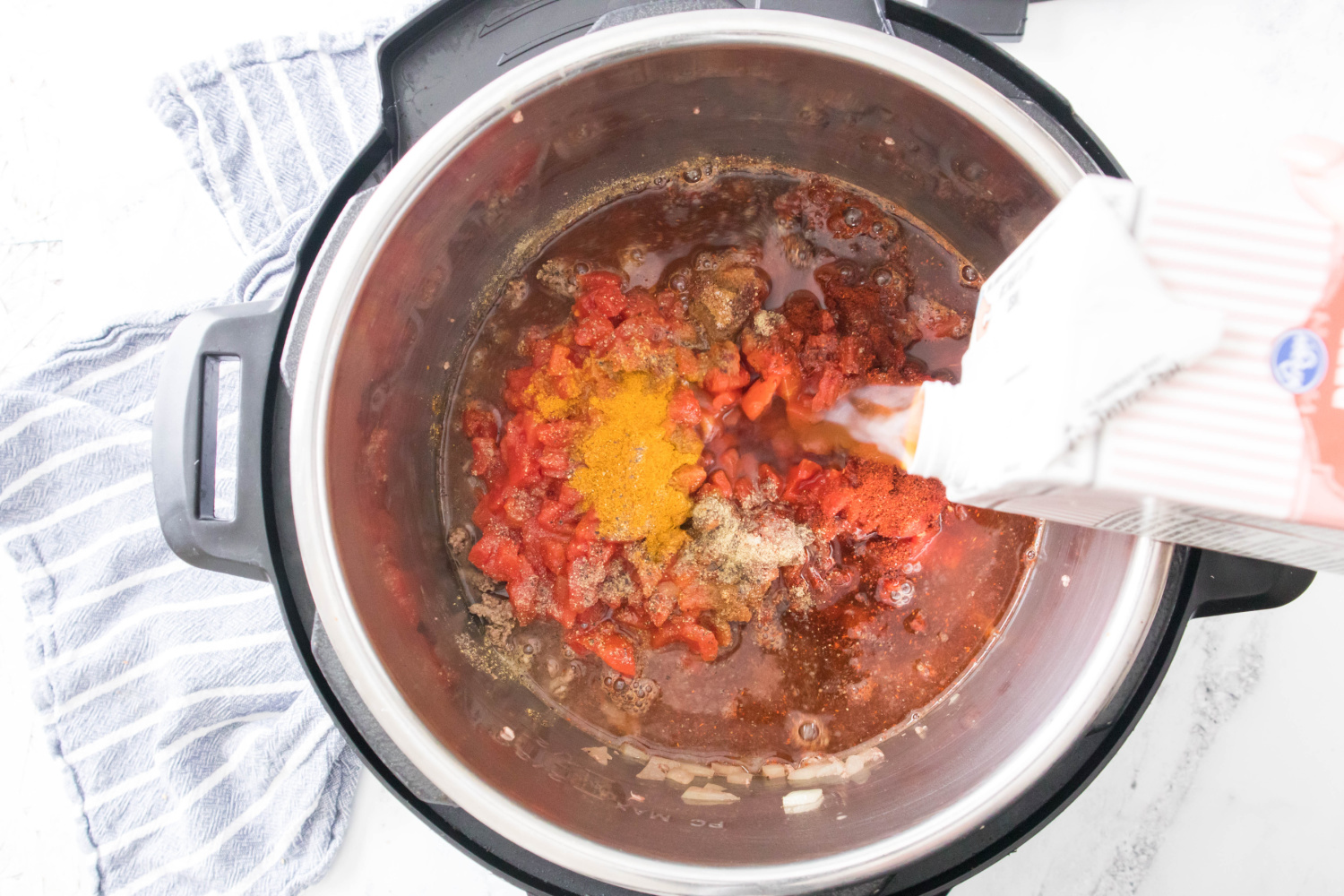 tomatoes, crushed or diced tomatoes, cumin, chili powder, curry powder, and beef broth added to instant pot